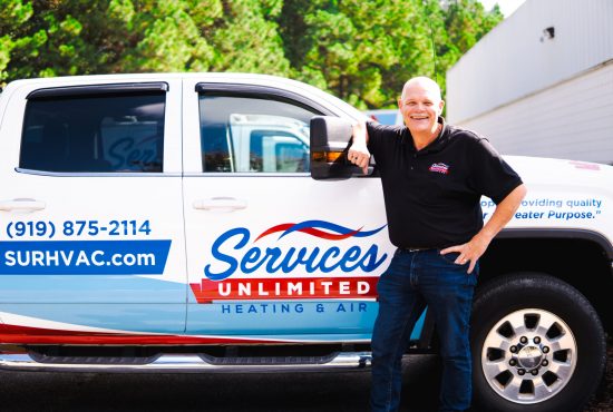 Clint Jones, owner of Services Unlimited, smiling proudly in front of his company truck