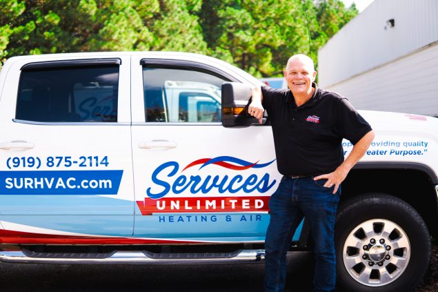 Clint Jones, owner of Services Unlimited, smiling proudly in front of his company truck